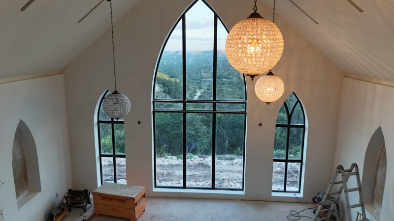 Interior of The Chapel at Wimberley with a vaulted ceiling, crystal chandeliers, and an arched window framing the Texas Hill Country